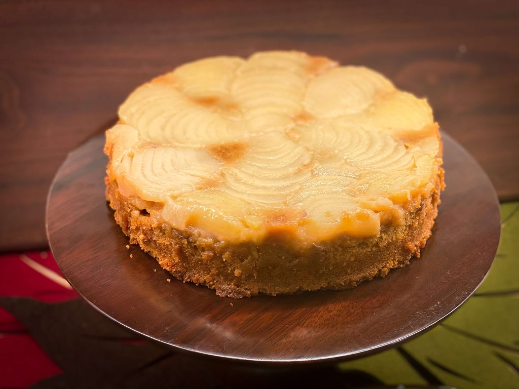 Upside down pear Cake un-molded on to a cake stand.