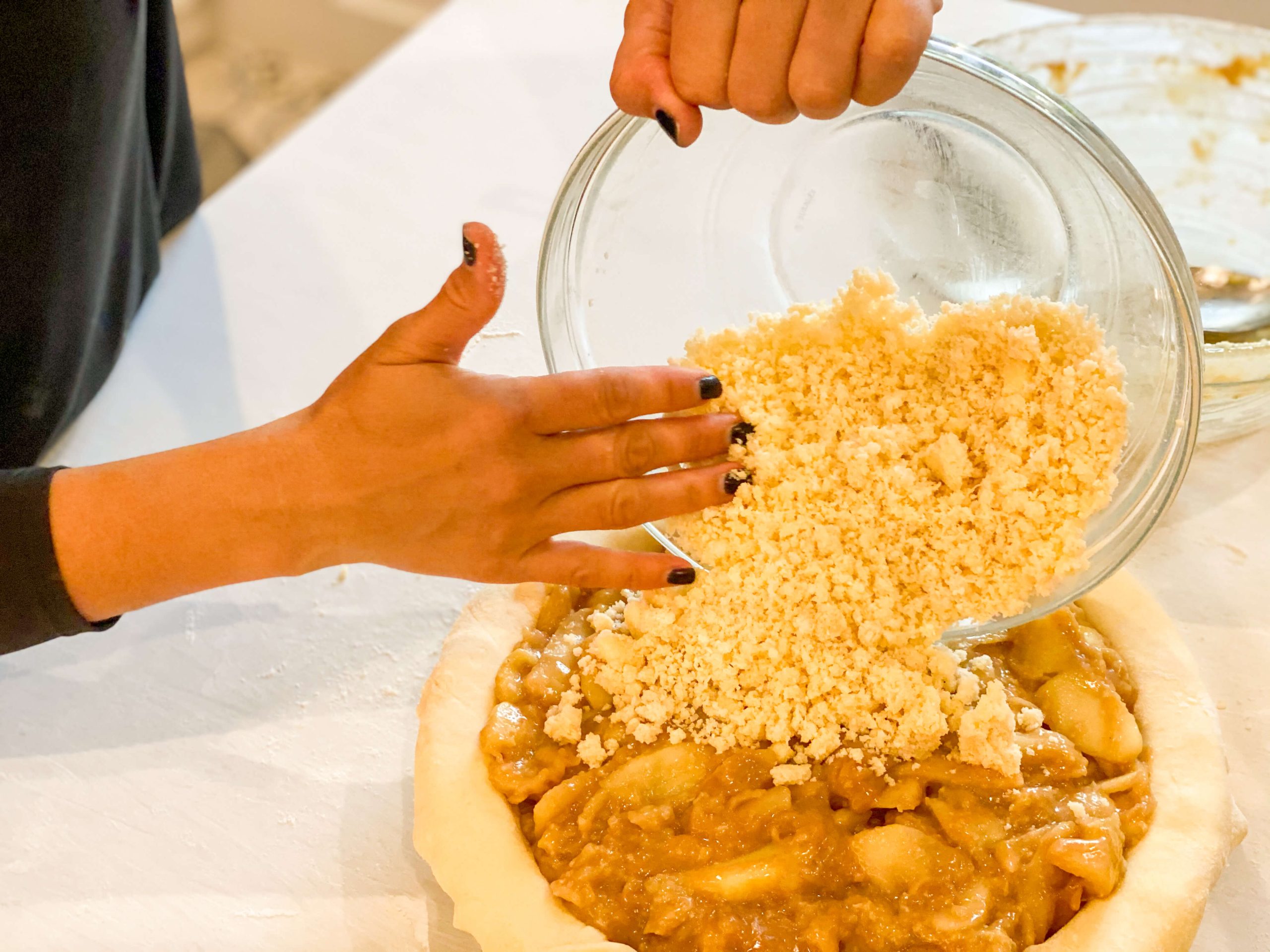 coconut crumble being poured on top of the cooked apples