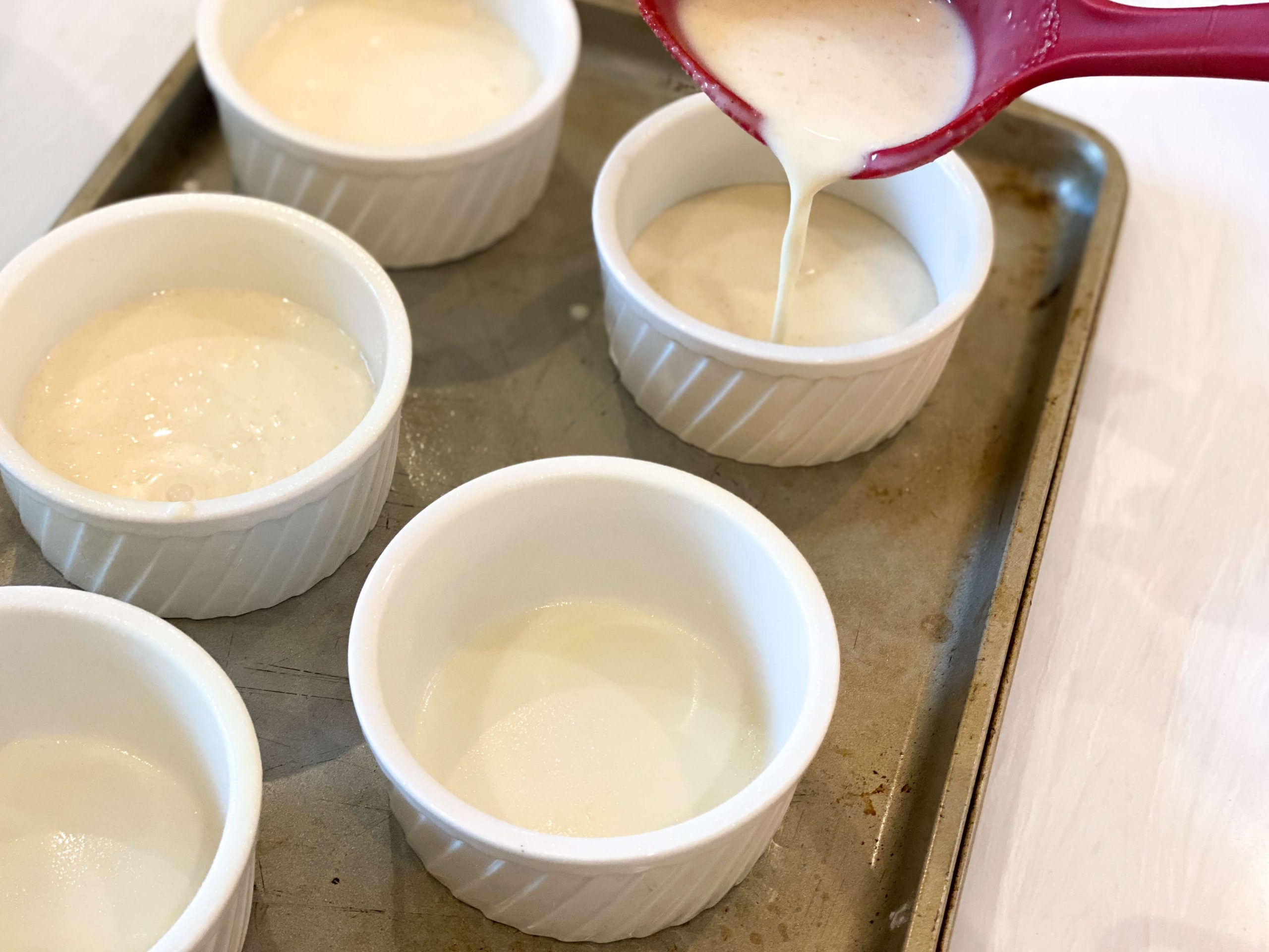 ramequins being filled with panna cotta heavy cream mixture