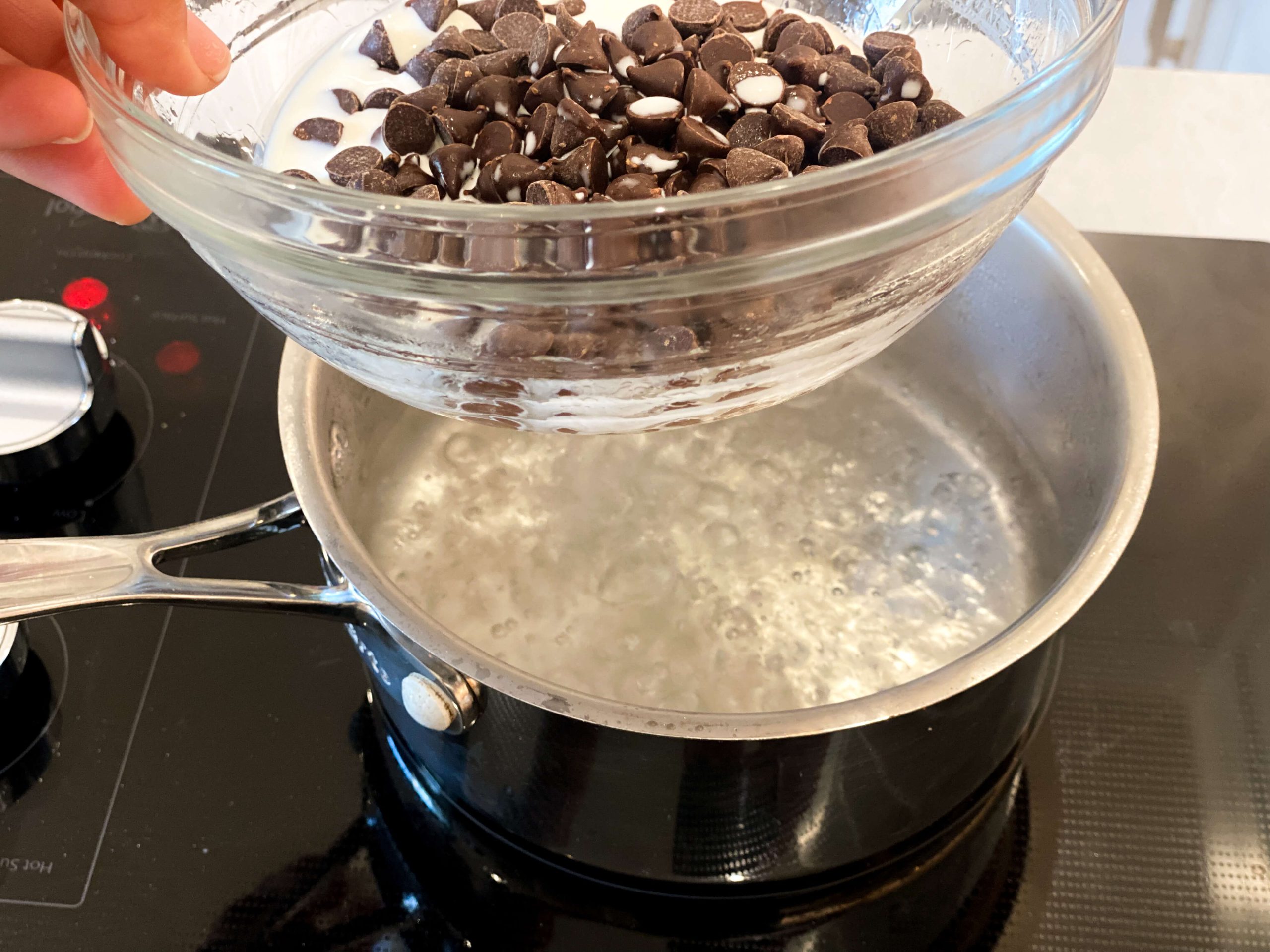 water boiling with glass bowl on top and chocolate chips