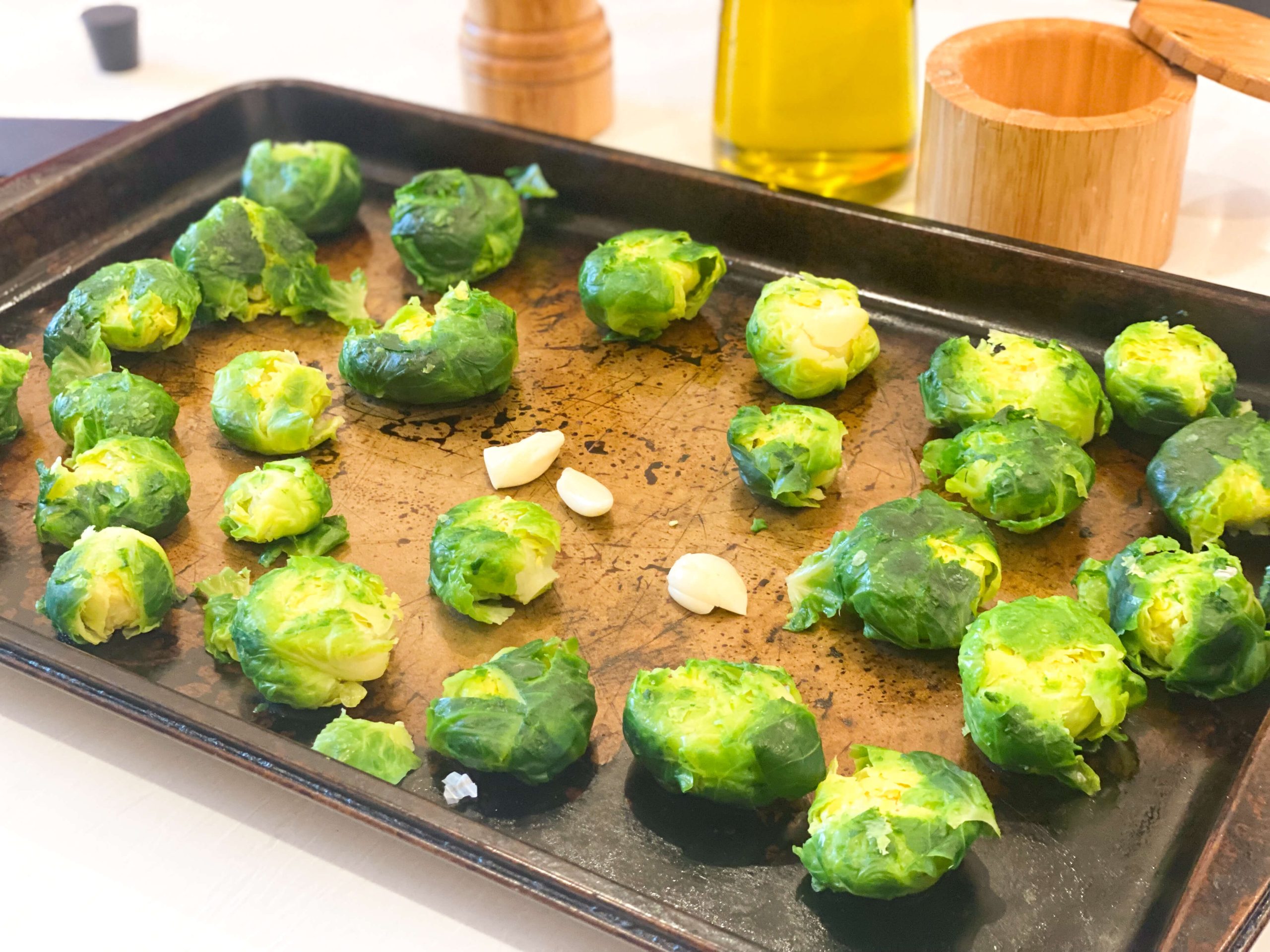 brussel sprouts and garlic cloves in large cooking sheet with extra virgin olive oil drizzled and salt and pepper. 