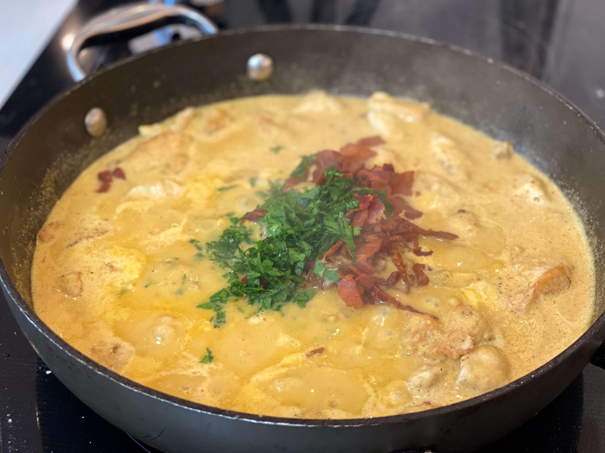 chicken cooking in the sauce with bacon and parsley 