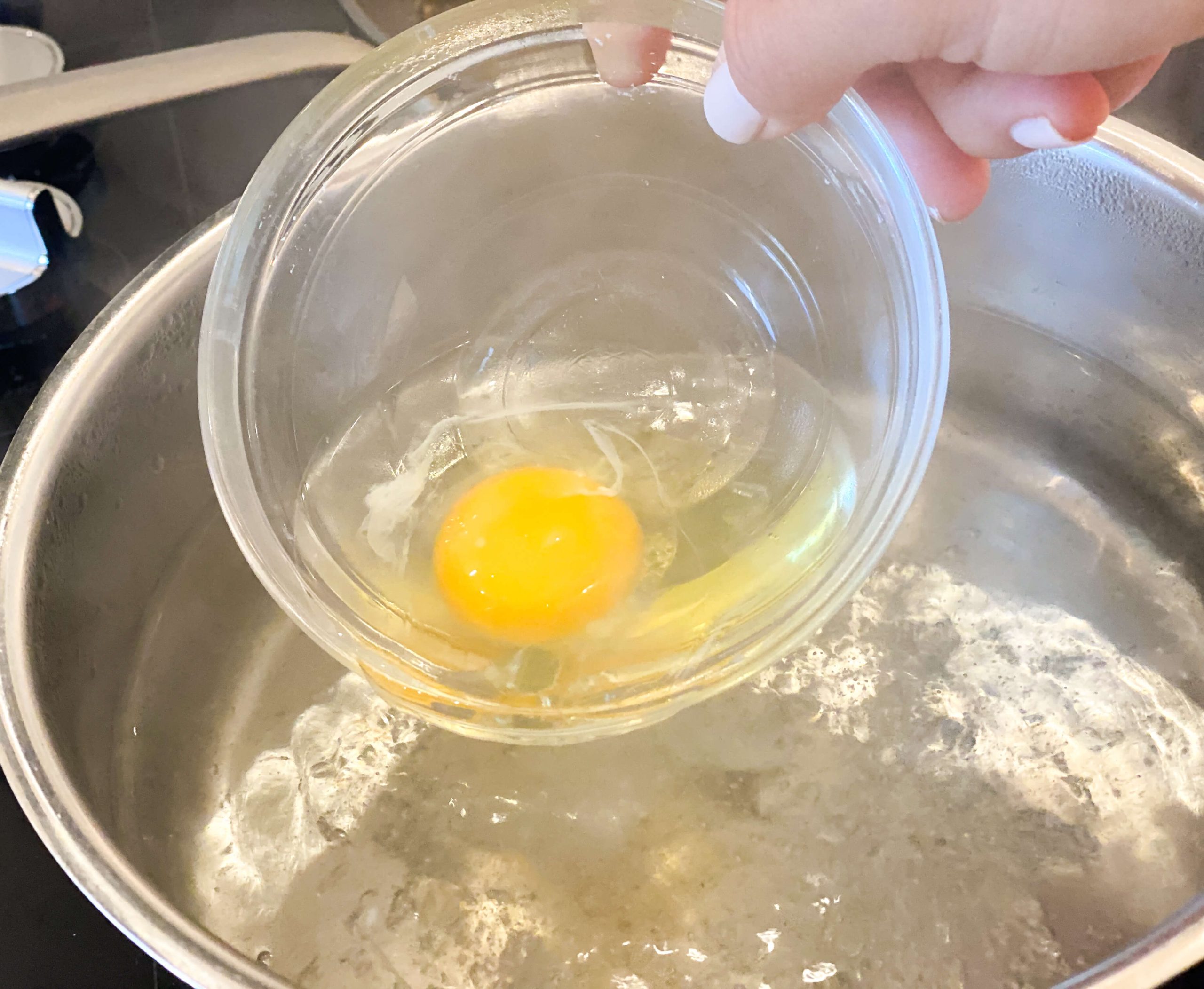 egg being dropped slowly into simmering water