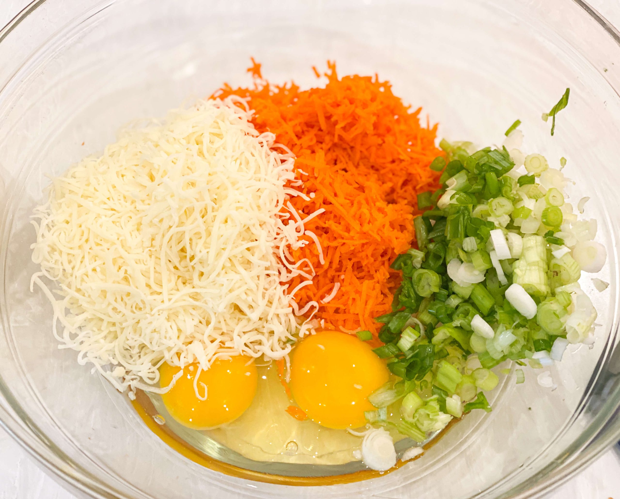 cheese, scallions, shredded carrots, and eggs in a bowl 