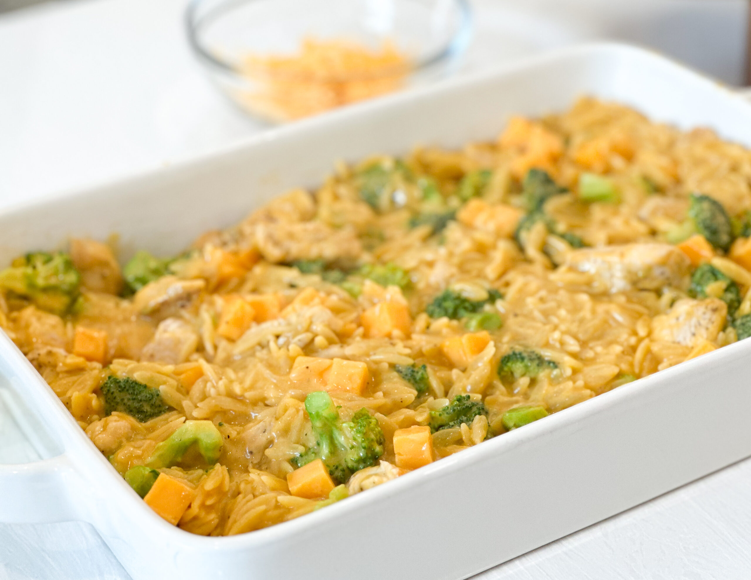 orzo in baking dish with cheddar cheese cubes