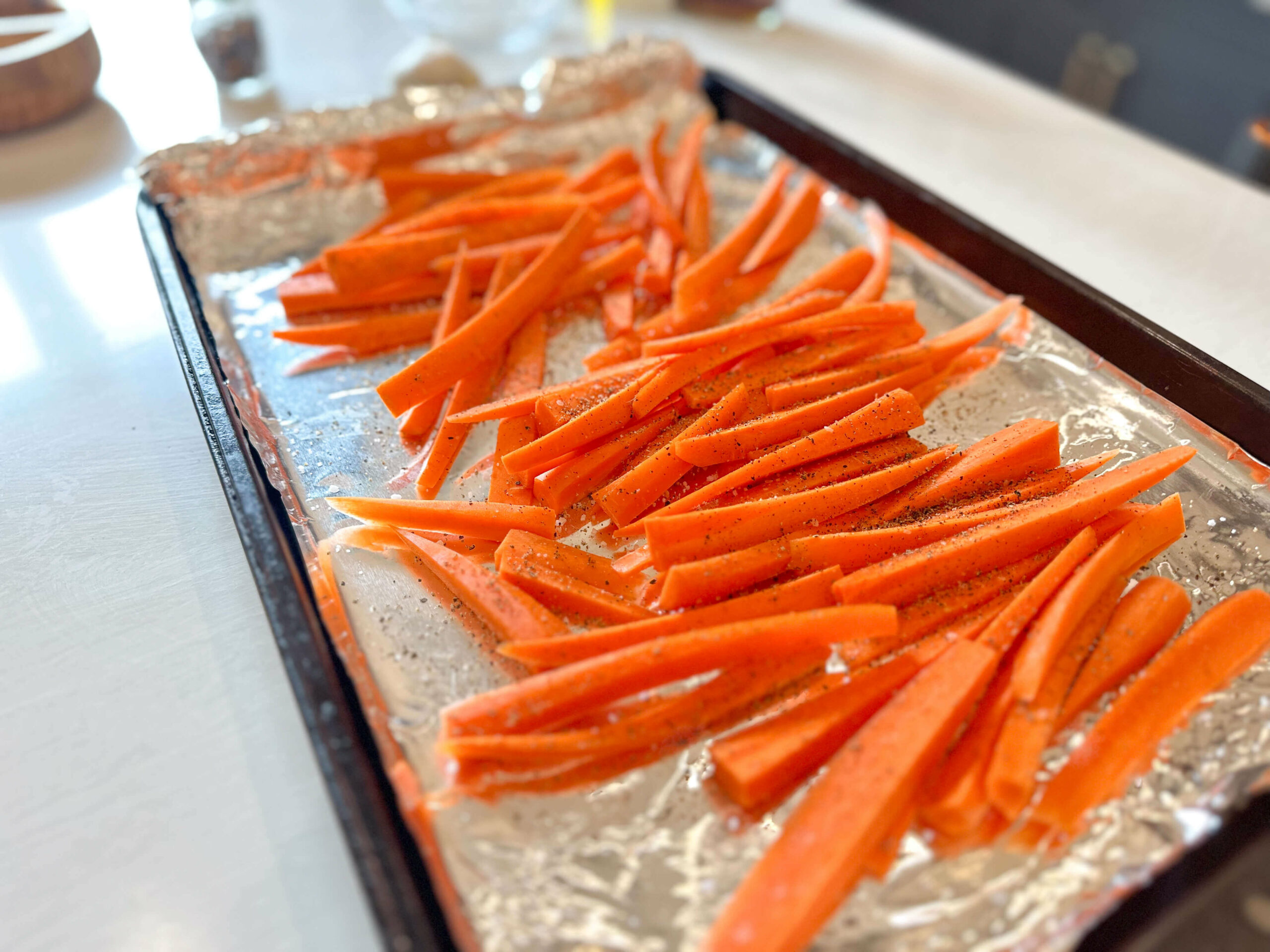 Carrots lined in baking sheet and seasoned with salt and a lot of freshly cracked pepper